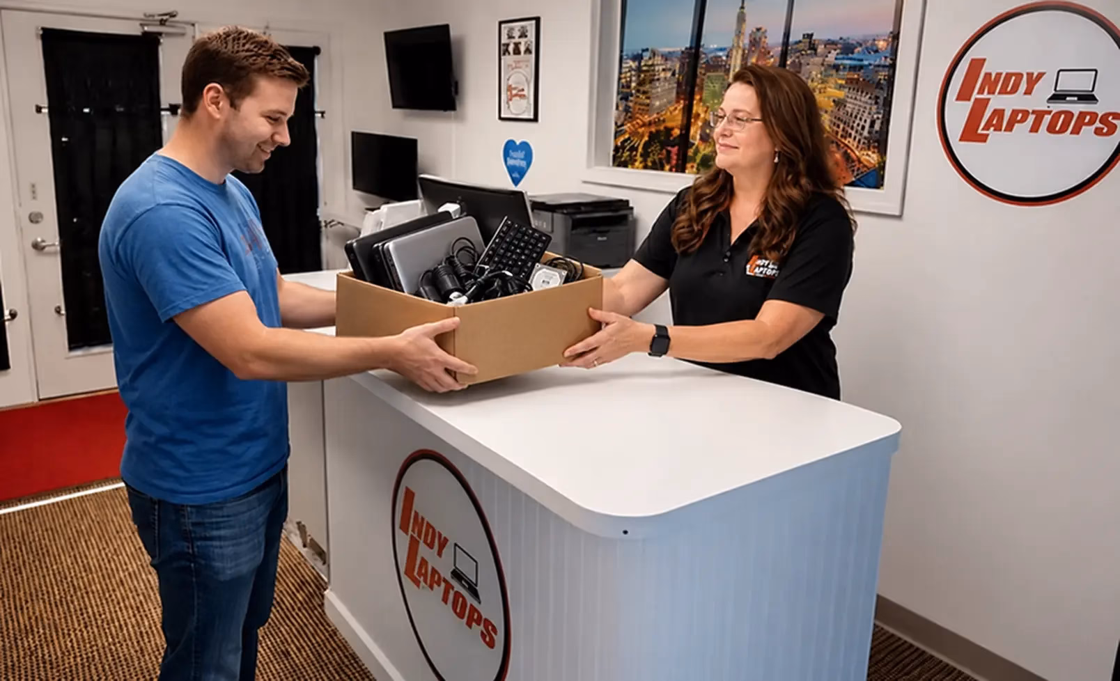 Customer handing a box of old laptops and computer components to an Indy Laptops employee for recycling